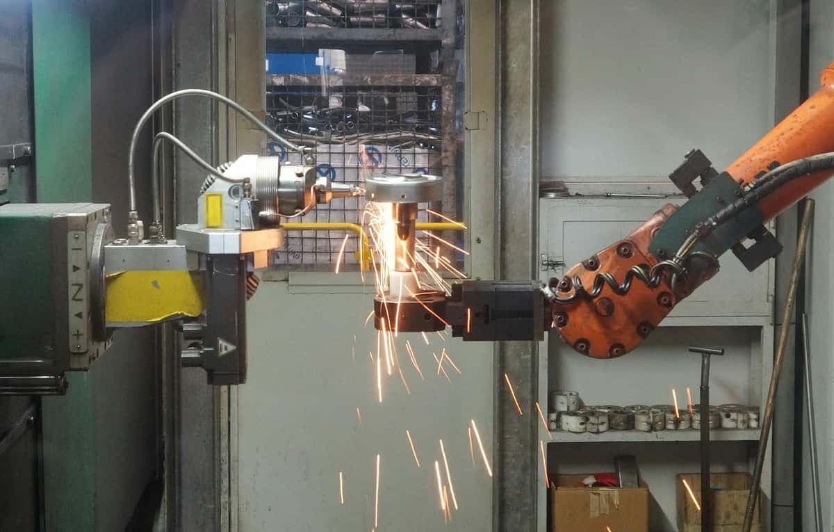 Industrial robot grinding steel with sparks in a manufacturing facility